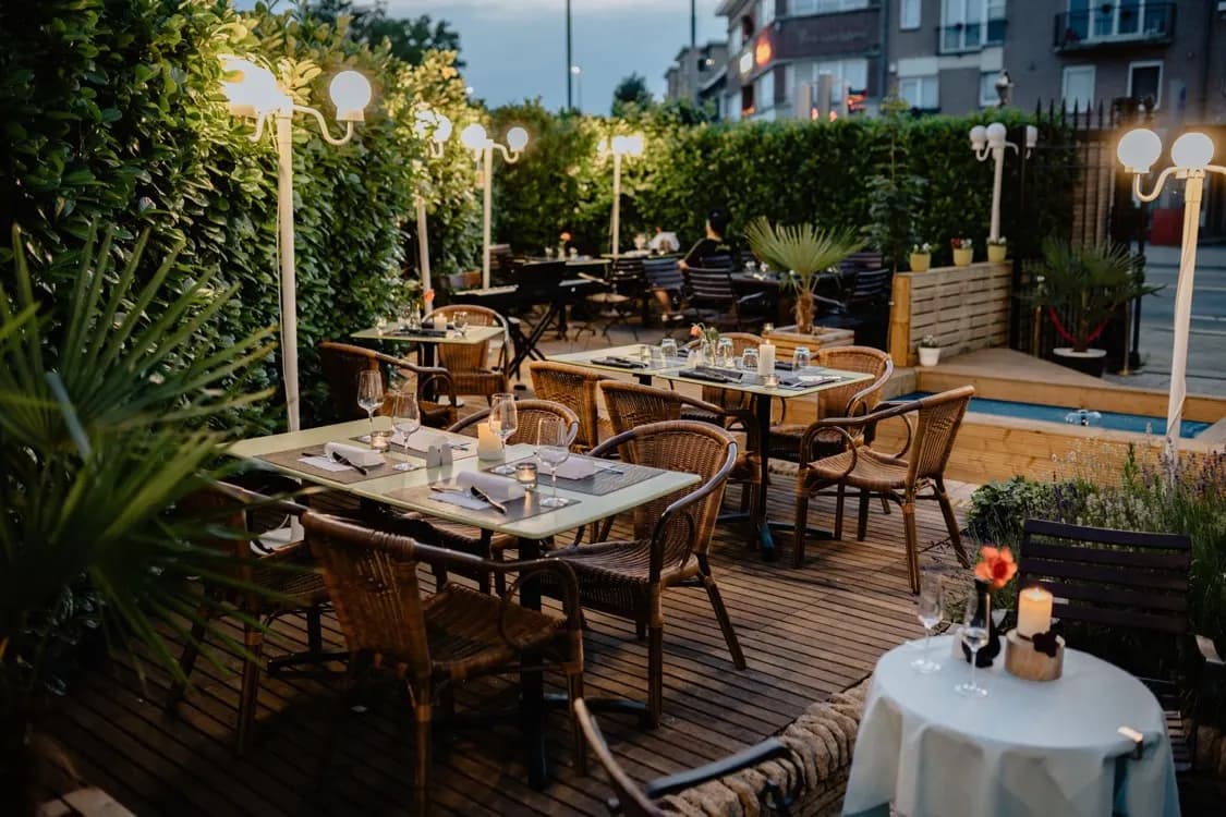 Outdoor terrace event space set with tables and warm evening lighting
