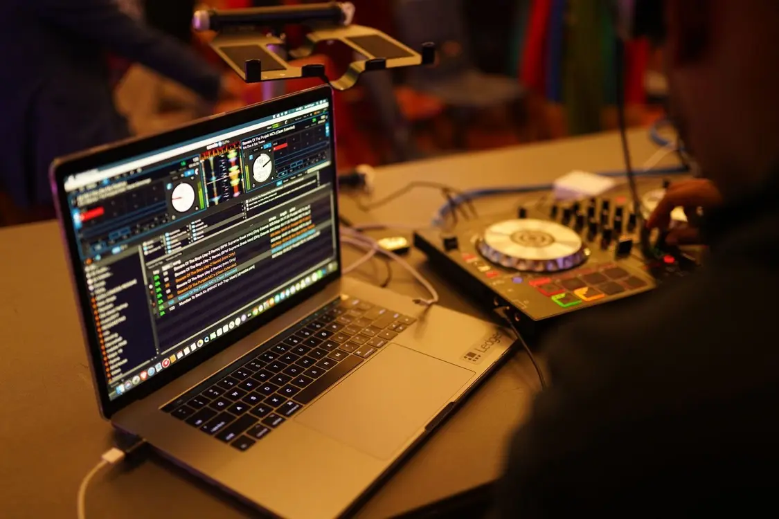 DJ working between a laptop running DJ software and a mixer controller