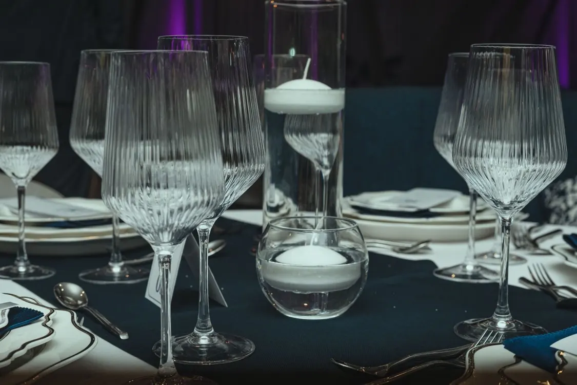 Elegant table setting with wine glasses and floating candles at a formal gala