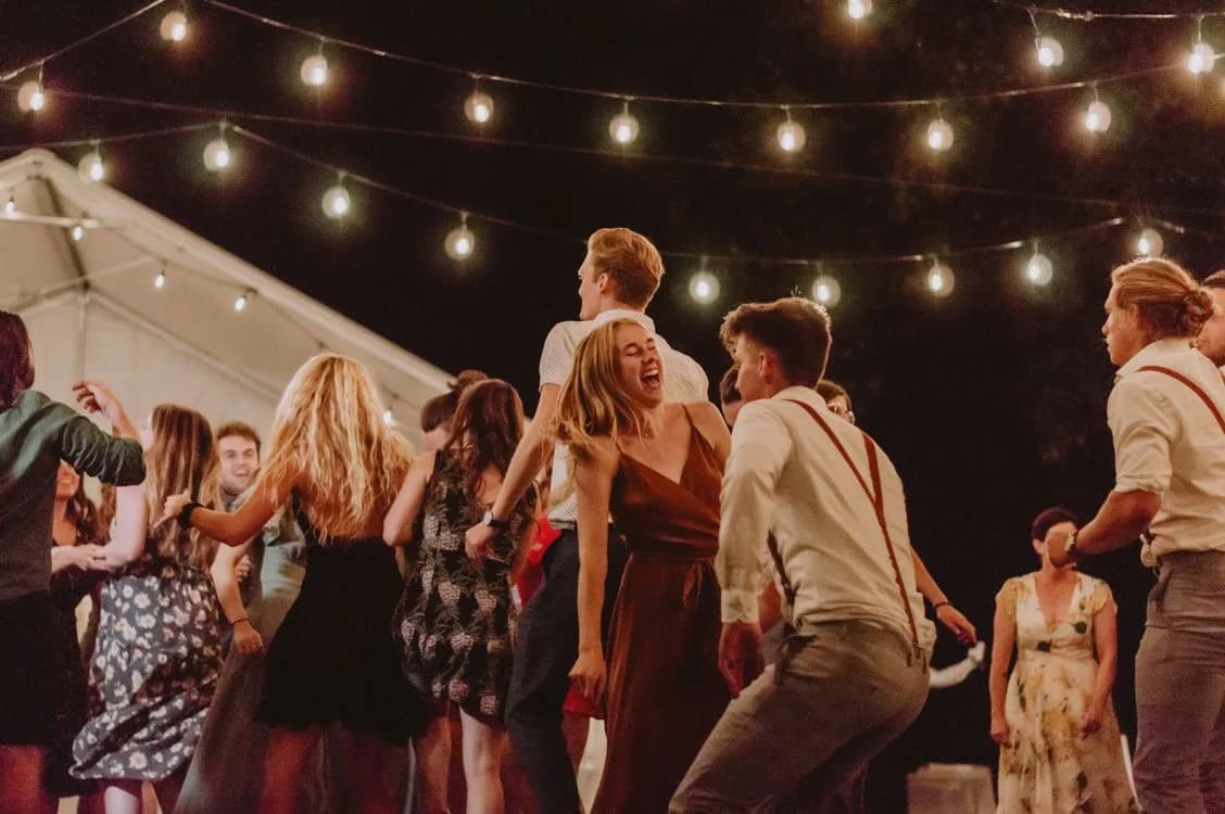 People celebrating at a joyful outdoor night party under string lights